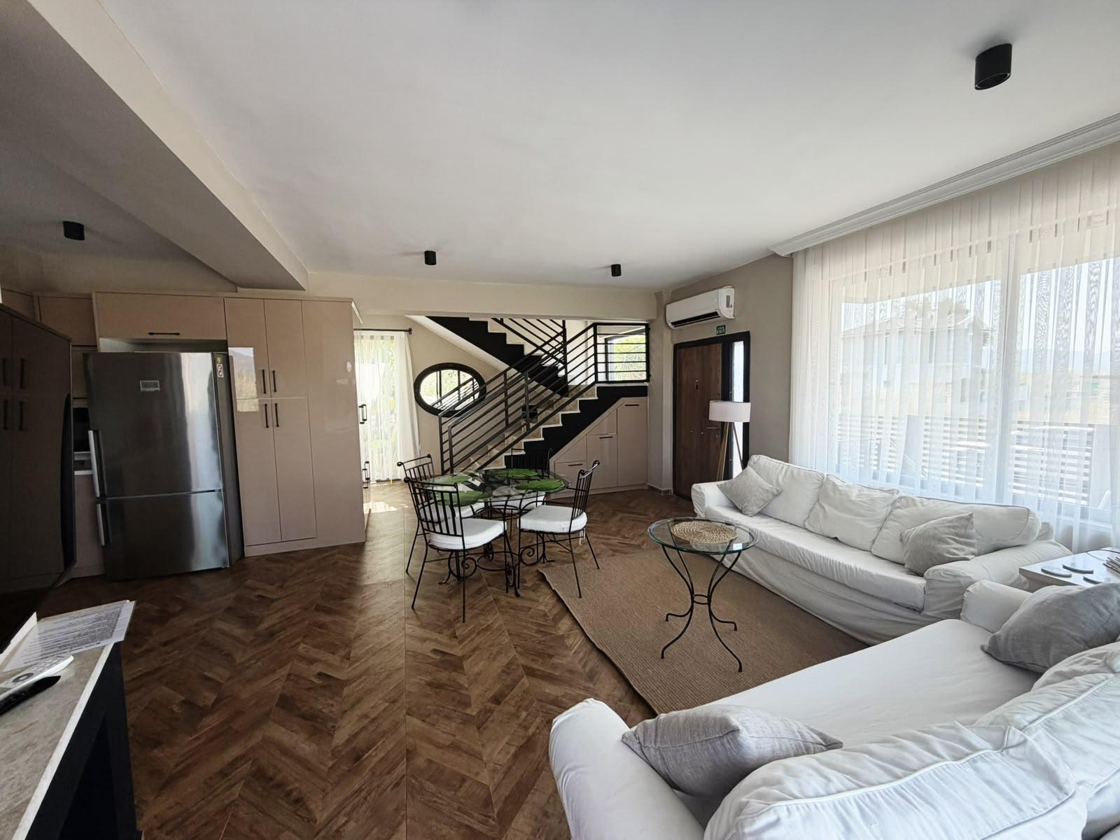 Living room with sofas, dining table and open kitchen
